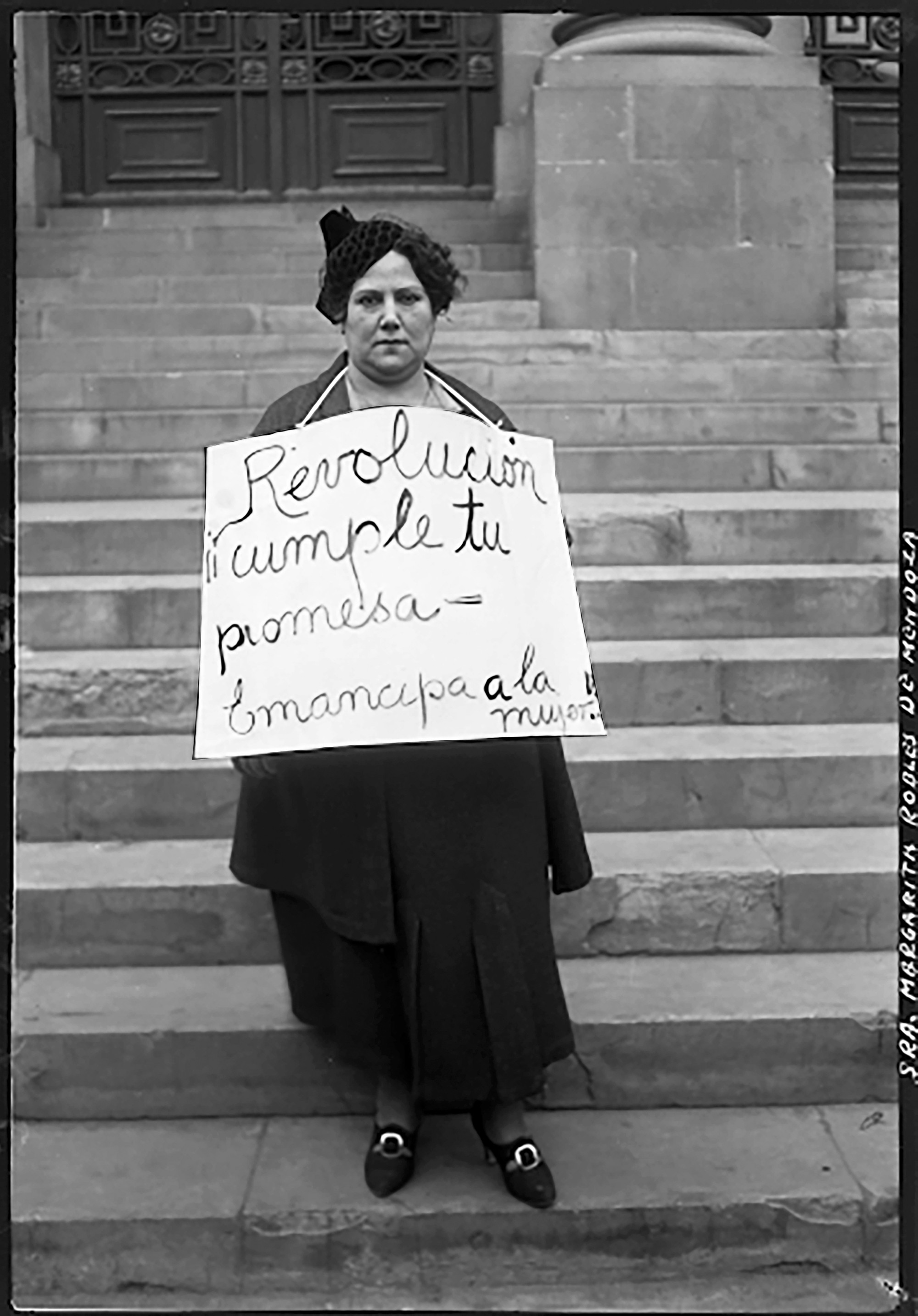 Image of Margarita Robles, a mexican feminist leader. She is holding a sign that reads: “Revolution, fulfill your promise, emancipate women!” The photograph is from 1934.